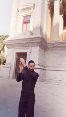 Tutkulu İspanyol adam geleneksel flamenko dansı yapıyor. Arkasında tarihi bir bina olan yetenekli bir erkek kurtarıcının düşük açılı çekimi.