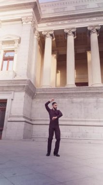 Genç İspanyol adam geleneksel flamenko dansını tutkuyla yapıyor. Klasik bir binanın önünde duygularını ifade eden profesyonel bir erkek dansçı.