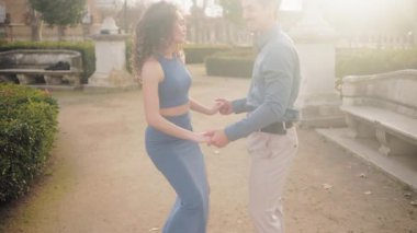 Tutkulu İspanyol çift gün batımında güzel bir parkta şehvetli bachata dansı yapıyor. Genç aşıklar romantik bir anın tadını çıkarıyor.