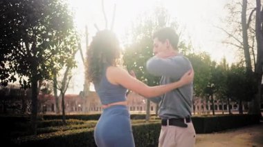 Güzel bir parkta tutkuyla dans eden genç İspanyol çift. Erkek ve kadın gün batımında şehvetli Latin ritimleri sergiliyor.
