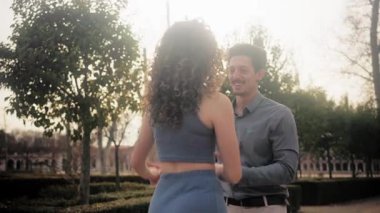 Tutkulu genç çift açık havada şehvetli bir bachata dansı yapıyor. Erkek ve kadın kucaklaşır ve parkta ritimle birlikte hareket ederler.