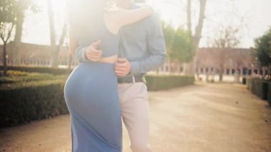 Romantik genç çift, Latin ritmini kucaklıyor ve dans ediyor. Gün batımında bir parkta tutkuyla hareket eden vücutlarını kapatın.