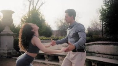 Genç İspanyol erkek ve kadın şehvetli bir bachata dansı yapıyorlar. Günbatımında güzel bir parkta tutku ve ritimle gösteri yapan profesyonel dansçılar.