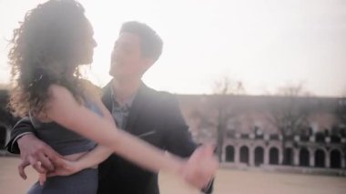 Genç İspanyol erkek ve kadın, sıcak bir akşam ışığı olan güzel bir şehir meydanında tutkulu ve şehvetli bir bachata dansı yapıyorlar.