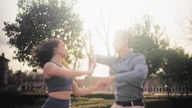 Neşeli çift gün batımında parkta şehvetli bir bachata dansı yapıyor. Latin dansçılar açık havada ritim, zarafet ve tutkuyla dans ediyorlar.