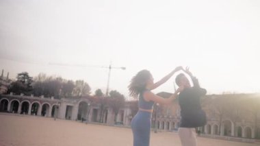 Güzel İspanyol çift, günbatımında şehir meydanında tutkulu ve şehvetli bir bachata dansı yapıyor.