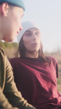 Genç lezbiyen çift güzel bir gün batımının tadını çıkarıyor, konuşuyor ve gülüyorlar. Doğada gerçek bir bağ ve mutluluk anı.