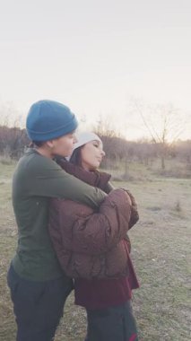 Güzel bir günbatımında romantik bir şekilde kucaklaşan iki genç İspanyol kadın. Mutlu lezbiyen çift birlikte hassas bir anın tadını çıkarıyor.