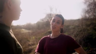 Açık havada romantik bir anın tadını çıkaran mutlu, genç lezbiyen çift. Gün batımında güzel bir parkta el ele tutuşan ve konuşan iki kadın.