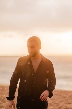 Sahil şeridinde içsel ve şehvetli hisseden bir adam. Rüya, ilham ve seyahat kavramları altın saat ışığı ile