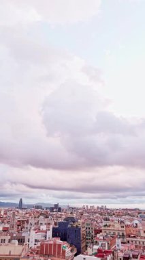 Barselona, İspanya 'nın havadan görünüşünü süpürüyor. Çatılar ve modern gökdelenler, Torre ihtişamı da dahil, dramatik bulutlu bir gökyüzü altında