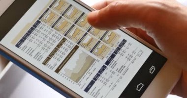 4k işadamı, Finansal Haberler cep cep telefonu üzerinde tarama parmak dokunmadan Finans pasta grafikler.