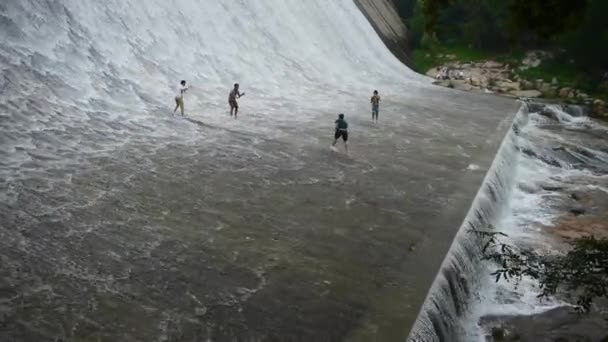 Проливной водопад и шпиндель, мальчик играет в воду под плотиной. — стоковое видео