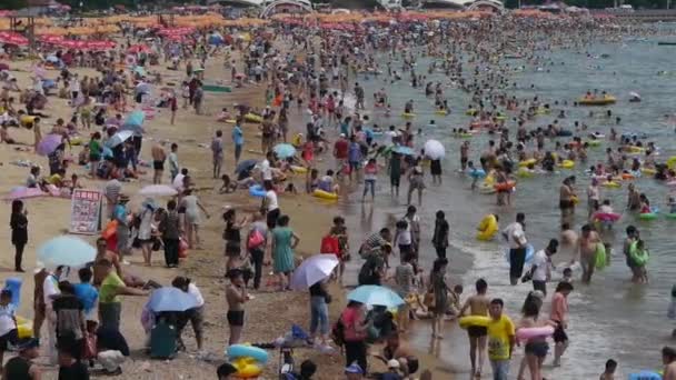 Mucha gente en la concurrida playa de arena de baño.La gente nada en el mar, Qingd de China — Vídeos de Stock
