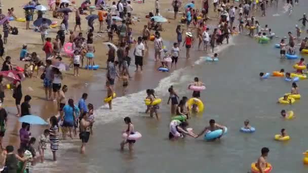 Mucha gente en la concurrida playa de arena de baño.La gente nada en el mar, Qingd de China — Vídeos de Stock