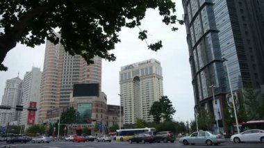 Şehir kavşağı sokağı, meşgul insanlar, ağaçlar, cam perde duvarı.