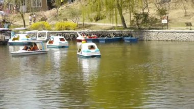 Işıl ışıl göl kenarındaki yoğun söğütler, turistler su üzerindeki gemilerde geziyorlar.