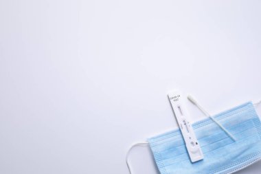 Hızlı Coronavirus testi ve beyaz arka planda tıbbi maske. COVID-19 için hızlı test cihazı kullanarak negatif test sonucu. Metin için boş alan.