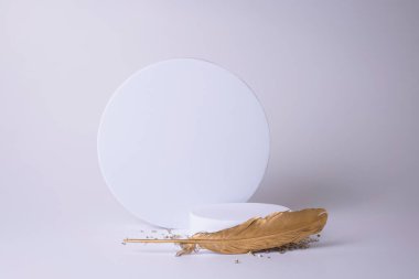 Beyaz arka planda altın tüy ve küçük kristallerle beyaz podyum. Ürün podyumu, kozmetik sunumu. Yaratıcı bir model. Güzellik ürünleri için kaldırım taşı veya platform.