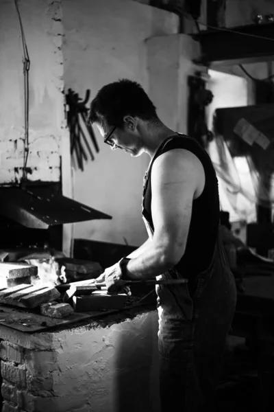 Le forgeron dans le processus de production de produits métalliques fabriqués à la main dans la forge. Photo noir et blanc — Photo