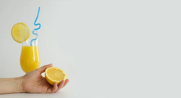 Jus d'orange frais en verre, décoré avec une tranche de citron et de paille bleue. Cocktail d'été sur fond blanc. Modèle coloré. Espace libre pour le texte, espace de copie. — Photo