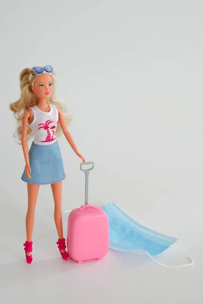 Doll with suitcase. Travel and flights during the time of COVID-19. Doll, medical mask, coronavirus antigentest on the white background. Vacation, holidays in corona times. Colorful design. — Stock Photo, Image