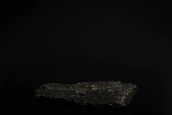 Podio de rock en el fondo negro. Piedra podest para el producto, presentación cosmética. Una maqueta creativa. Pedestal o plataforma para productos de belleza. — Foto de Stock