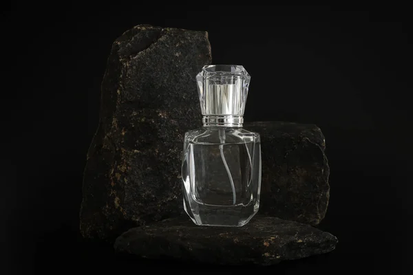Márkátlan parfümös üveg áll a kődobogón. Parfüm bemutató a fekete háttérben. Mockup. Trending koncepció a természetes anyagokban. Nők és férfiak esszenciája. Természetes kozmetikai termék. — Stock Fotó