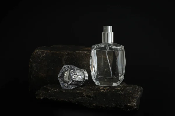Márkátlan parfümös üveg áll a kődobogón. Parfüm bemutató a fekete háttérben. Mockup. Trending koncepció a természetes anyagokban. Nők és férfiak esszenciája. Természetes kozmetikai termék. — Stock Fotó