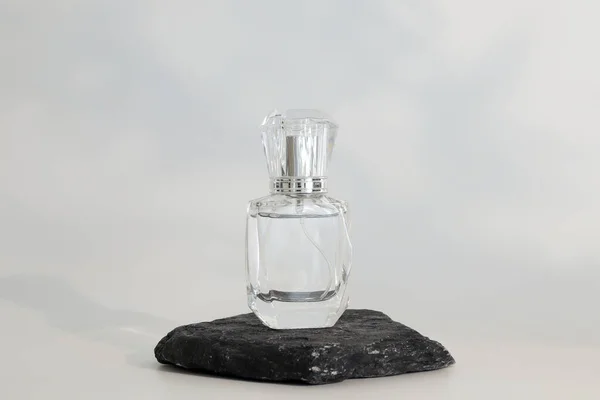Márkátlan parfümös üveg áll a kődobogón. Parfüm bemutató a fehér háttérben. Mockup. Trending koncepció a természetes anyagokban. Nők és férfiak esszenciája. Természetes kozmetikai termék. — Stock Fotó