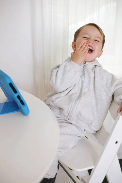 Menino feliz jogando jogo em tablet digital em casa. Retrato de uma criança em casa assistindo desenhos animados no tablet. Criança moderna e tecnologia de educação. — Fotografia de Stock