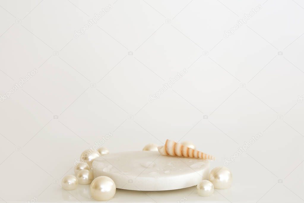 White marble podium with pearls, shells and water drops on the white background. Podium for product, cosmetic presentation. Creative mock up. Pedestal or platform for beauty products.