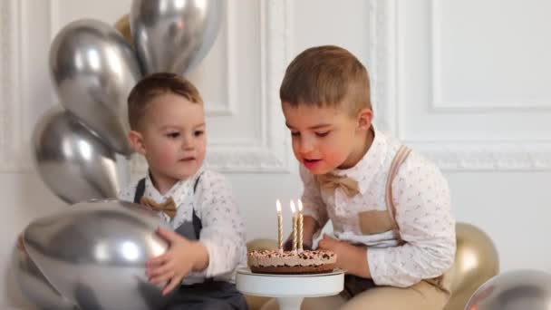 Deux garçons fêtent leur anniversaire, les enfants font une fête du jour B. Des enfants soufflant des bougies sur le gâteau d'anniversaire. Célébration, intérieur minimaliste blanc. — Video