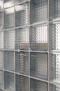 Cam bloklu bir duvarın yakın plan görüntüsü, modern odanın parlak atmosferini yükselterek dokulu yüzeyi ve şeffaflığı ön plana çıkarıyor..