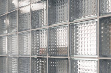 Şeffaf cam bloklar modern bir duvar oluşturarak ışığın boşluğa desen ve derinlik ekleyerek geçmesine olanak sağlıyor. Tasarım, geometrik şekillerle atmosferi güçlendirir..