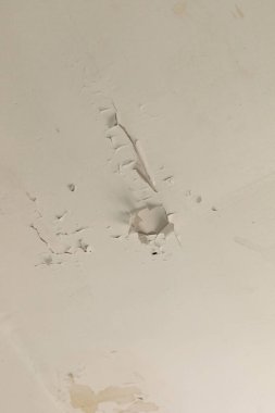 Eski bir evin tavanında belirgin çatlaklar ve boyalar görülüyor. Bu da uzun süreli ihmal ve bozulmaya işaret ediyor. Çevre terk edilmiş ve ihmal edilmiş gibi..