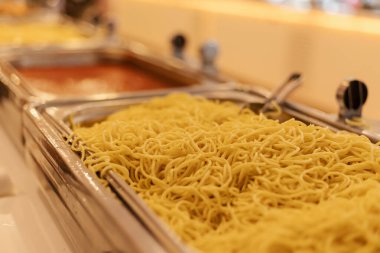 Birden fazla tepside açık büfe için hazırlanmış farklı türde erişte bulunur. Aydınlık ortam davetkar atmosferi artırıyor, öğle yemeği toplantıları için mükemmel hale getiriyor..