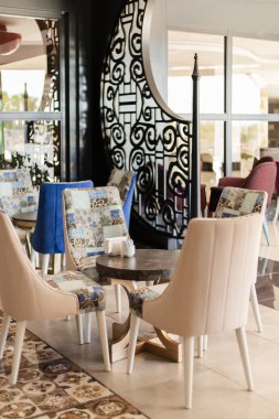 Sahne, lüks sandalyeleri ve masaları olan şık bir restoran içini gösteriyor. Duvarlardaki ve katlardaki dekoratif desenler lokantalar için davetkar atmosferi arttırır..