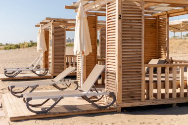 Gölgeli alanları olan plaj kabinleri kumlu sahillerde rahat dinlenme yerlerinin yanında duruyor. Parlak güneş ışığı rahatlamak ve keyif almak için davetkar bir atmosfer yaratır..