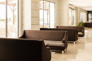 Oturma alanı parlak, ferah bir kafede düzenlenmiş şık kahverengi koltuklara sahiptir. Geniş pencereler odayı doğal ışığın doldurmasına izin veriyor ve davetkar bir atmosfer yaratıyor..