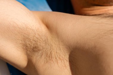 Bir birey koltuk altının görünürdeki kısa saçlarıyla tüylerini aldırma seçeneklerini gözler önüne seriyor. Bu sahnede vücut bakımına ve yaz hazırlıklarına önem veriliyor..