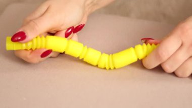 Parmaklar esnek sarı bir plastik tüpü manipüle ederek sıkıştırılmış ve parçalanmış benzersiz tıkırtı sesleri çıkarıyor. Bu enstrümanla eğlenceli etkileşimlerin tadını çıkarın.