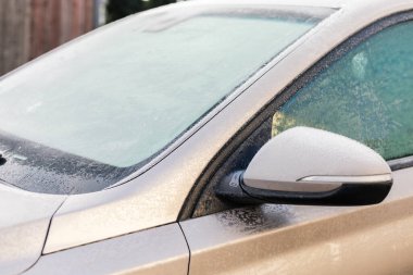 Soğuk bir kış sabahı park etmiş bir araba, pencereleri ve yüzeyleri kalın bir buz tabakasıyla kaplıdır. Buzlu hava bu mevsim için tipik düşük sıcaklıklara işaret ediyor..