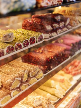 Bir dükkanın içindeki cam kutularda çeşitli renkli tatlılar düzenli olarak düzenlenir. Müşteriler seçimleri gözden geçirir ve hareketli atmosferin tadını çıkarırlar..