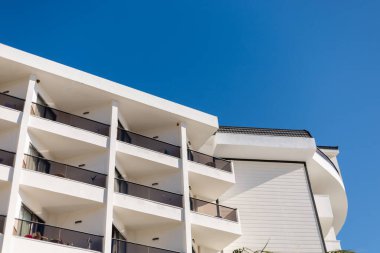 Binanın çok sayıda balkonu ve beyaz bir dış yüzeyi vardır. Yapı parlak mavi bir gökyüzüne karşı konumlandırılmıştır. Görünürde hiç bulut yok..