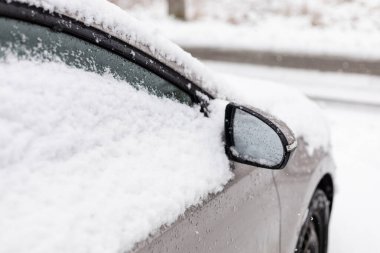 Yolda park edilmiş bir araba var. Kar arabanın üstüne ve pencerelere yığılmıştır. Kış mevsimindeyiz ve gri gökyüzünden taneler düşüyor. Kar yağışı nedeniyle görüş mesafesi düşük.