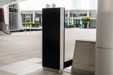 Binanın girişinde boş bir tabela duruyor. Alan açık ve arka planda ağaçlar olan temiz hatlara sahiptir. Bu alanın çağdaş bir tasarımı ve basit bir düzeni var..