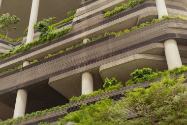 Bina, her katta farklı bitki ve yeşillik katmanları barındırıyor ve eşsiz bir tasarım sağlıyor. Yapının beton sütunları ve modern çizgileri var..