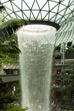 Singapur - 27 Ocak 2026: İnsanlar Singapur 'daki Jewel Changi Havalimanı' nı keşfediyor. Cam tavandan süzülen büyük şelaleye hayranlar. Bölgeyi saran yemyeşil bitkiler