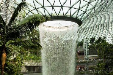 Singapur - 27 Ocak 2026: Ziyaretçiler Singapur 'un yeşil ve modern mimarisi ile çevrili, çatıdan çağlayan büyük bir şelale olarak Jewel Changi Havalimanı' nı keşfediyorlar..